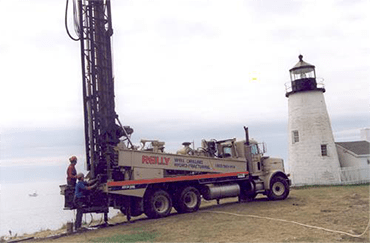 A well-drilling truck near a lighthouse